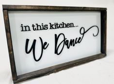 a sign that says in this kitchen we dance on the side of a white wall