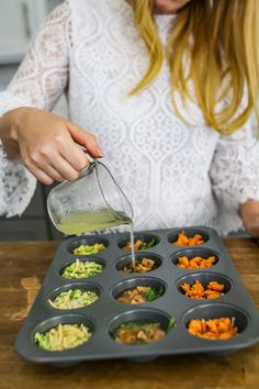 a woman pours dressing into a muffin tin filled with carrots and celery