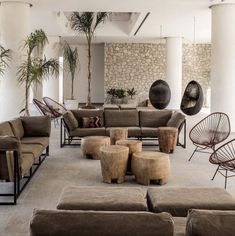 a living room filled with lots of furniture next to a stone wall covered in plants