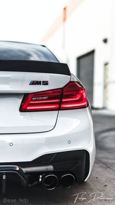 the rear end of a white car parked in a parking lot