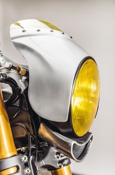 a close up of a motorcycle headlight on a white and gold motorbike