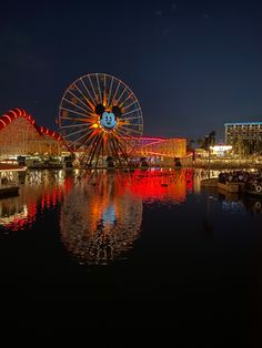 an amusement park at night with lights reflecting in the water