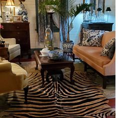 a living room filled with furniture and lots of pillows on top of a zebra print rug