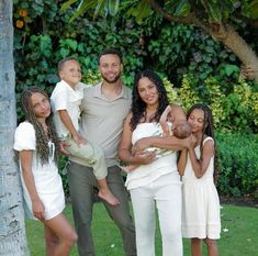 a man and two women are posing with their children in front of a palm tree