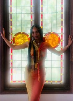 a woman standing in front of a stained glass window with her arms out and hands outstretched