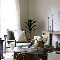 a living room filled with furniture and a clock on top of a table in front of a window