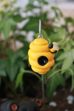 a yellow beehive pin sitting on top of a green plant