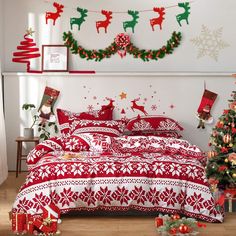 a bedroom decorated for christmas with red and white bedding, stockings and decorations on the wall