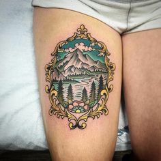 a woman's thigh with a mountain and forest tattoo on the side of her leg