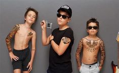 three young boys standing next to each other with tattoos on their arms and chestes