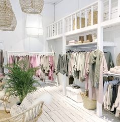 a room filled with lots of clothes and baskets on top of the shelves next to a potted plant