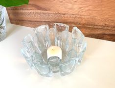 a glass candle holder sitting on top of a table