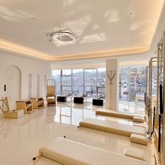 a large room with lots of white furniture and windows overlooking the city in front of it