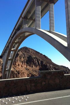 an overpass on the side of a road with mountains in the backgroud