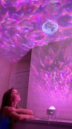 a girl is looking up at the ceiling that has lights on it and stars in the sky