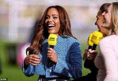 two women are talking to each other while one is holding a microphone and the other holds a yellow object