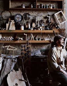 a man sitting on a chair in a room filled with lots of items and tools