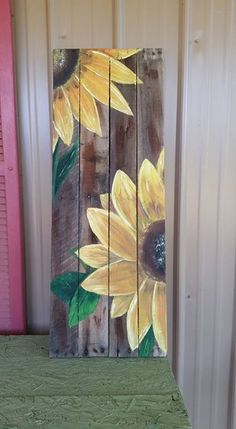 a painting of sunflowers painted on wooden planks in front of a pink door