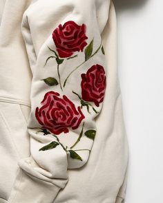 a white sweatshirt with red roses embroidered on it