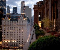 the building is lit up at night in front of other tall buildings and skyscrapers