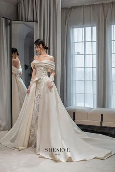 a woman in a white wedding dress standing next to a mirror