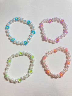 four bracelets with different colors and designs on them, all made out of plastic beads