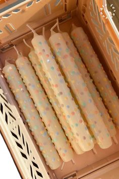 four candles are lined up in an open box with polka dots on them and one is white