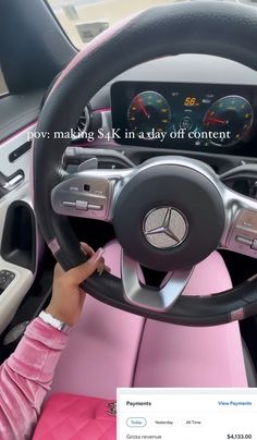 a woman driving a pink car with the steering wheel up