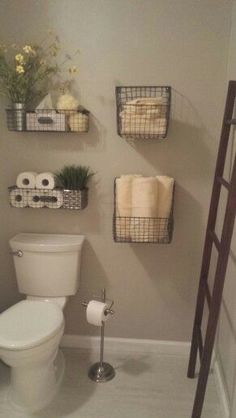 a white toilet sitting in a bathroom next to a wooden shelf filled with towels and other items