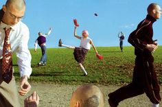 a group of people are running around in the grass and one man is wearing a tie