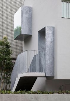 an apartment building with stairs and balconies on the outside, next to a tree