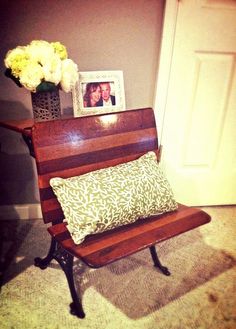 a wooden bench sitting in front of a door next to a vase with flowers on it