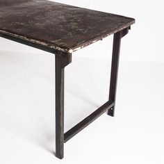 an old table that has been turned into a dining table with metal legs and a rusted surface