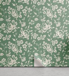 a green wallpaper with white flowers on it and a roll of paper next to it