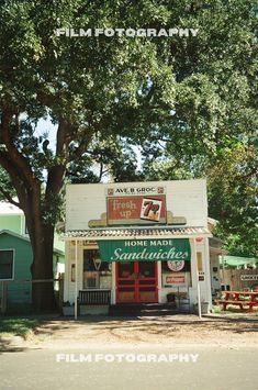 an old fashioned store sits on the side of the road in front of a large tree