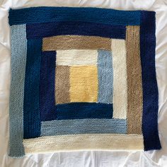 a close up of a knitted square on a white sheet with blue and yellow squares