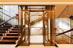 an elevator with glass walls and stairs leading up to the second floor