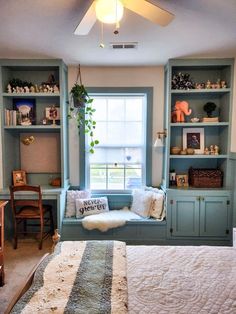 a bed sitting under a window next to a book shelf filled with lots of books