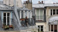 a person standing on a balcony next to some buildings with windows and balconies