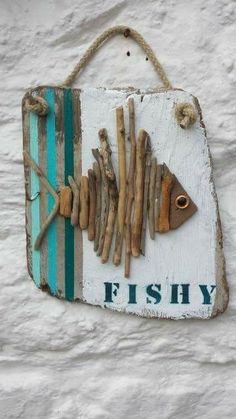 a fishy sign hanging on the side of a building with driftwood in it