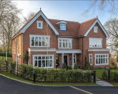 a large brick house with lots of windows on it's sides and bushes in the front yard