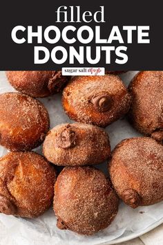 chocolate donuts are piled on top of each other with powdered sugar sprinkled on them