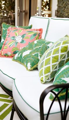 a white couch with green and pink pillows on it