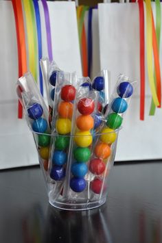 a plastic cup filled with lots of colorful candies on top of a black table