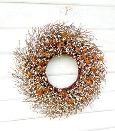 a wreath is hanging on the side of a white building with brown and orange flowers