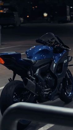 a blue motorcycle is parked in the parking lot near some buildings at night with its lights on