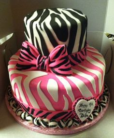 a pink and black zebra print cake with a heart on the top, sitting in a box