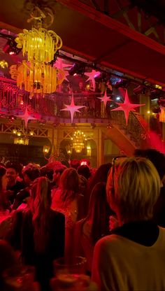 a group of people in a room with chandeliers and stars hanging from the ceiling