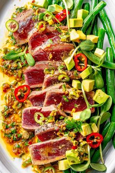 a white plate topped with meat and veggies next to green beans on a table