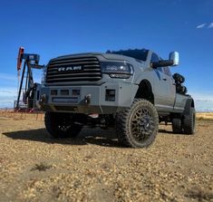 a large gray truck parked on top of a dirt field next to an oil pump